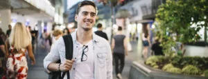 happy man standing on sidewalk with his backpack